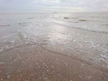 Close-up of wet sand on beach against sky