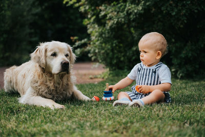 Cute toddler with dog sitting on lawn