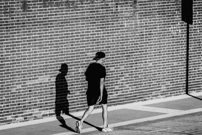 People walking on sidewalk against brick wall