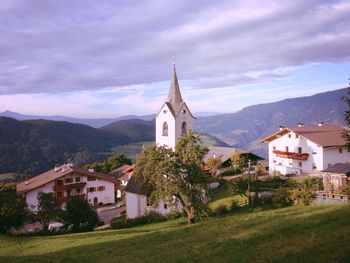 Buildings and mountain range against cloudy sky