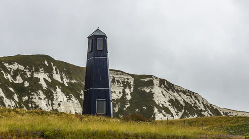 Low angle view of lighthouse amidst buildings against sky