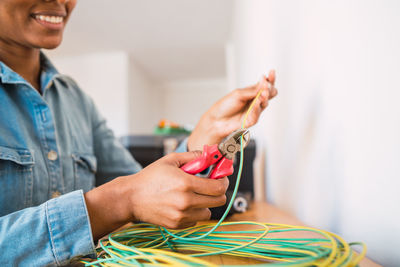 Mid adult woman cutting cable with wire cutter at home