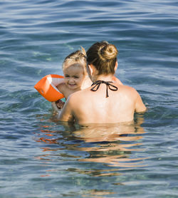 Rear view of shirtless woman in sea
