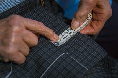 Close-up of tailor measuring textile with tape measure