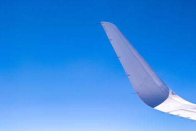 Low angle view of airplane flying against clear blue sky