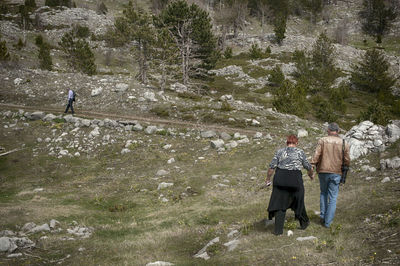 Rear view of people walking on street amidst trees