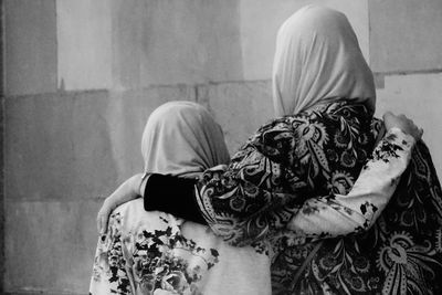 Rear view of sisters in hijab with arms around