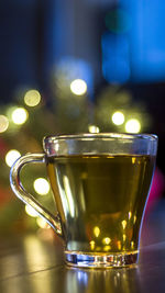 Close-up of glass of drink on table with bokeh christmas lights in the background