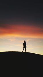 Silhouette man standing against sky during sunset