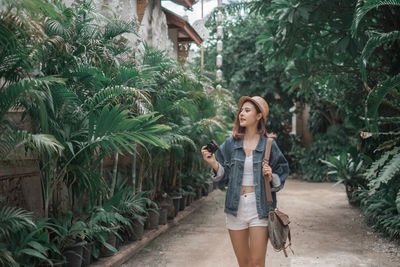 Young woman standing on footpath amidst plants