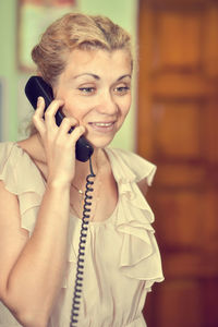 Smiling woman talking on telephone at home