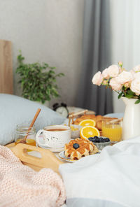 Romantic breakfast with coffee, waffles, orange juice and rose flowers.