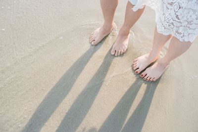 Low section of woman with shadow on sand