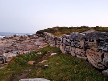 Rocks by sea against clear sky