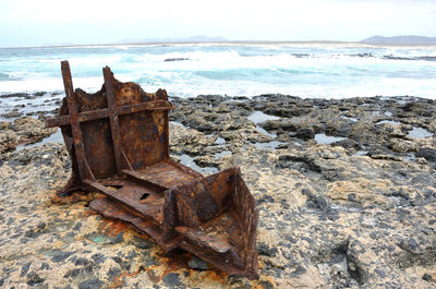 Rusty metal on beach against sky