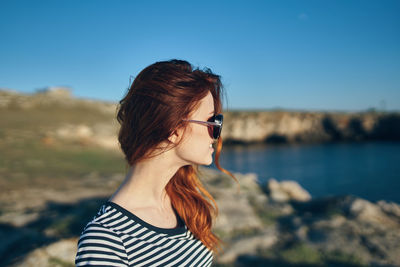 Portrait of young woman wearing sunglasses against sky