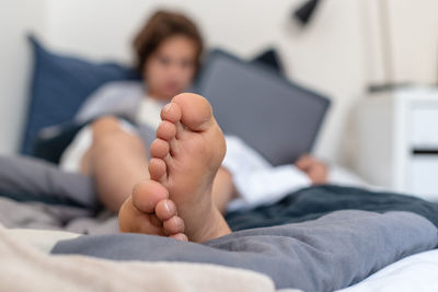 Surface level view of teenage boy using laptop on bed