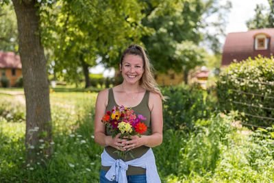 Portrait of smiling young woman holding flowering plants