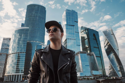 Low angle view of man standing by modern buildings in city