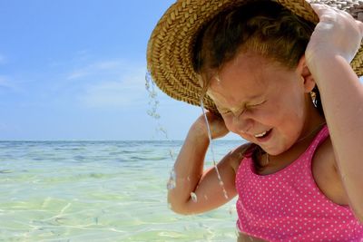 Girl wearing hat on beach against sky