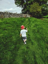 Rear view of boy walking on grassy field