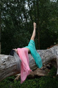 Midsection of woman with arms raised in forest