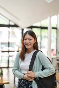 Portrait of young woman standing in cafe