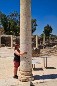 Side view of woman hugging historic column