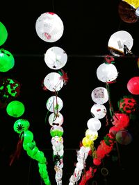 Low angle view of illuminated lanterns hanging against black background