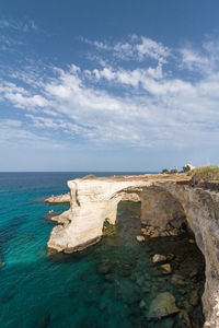 Scenic view of light blue and crystal clear sea against white clouds sky