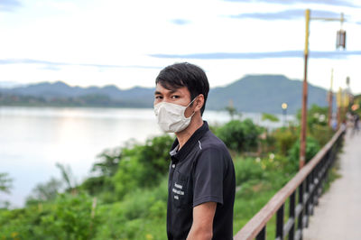 Portrait of young man standing on mountain against sky