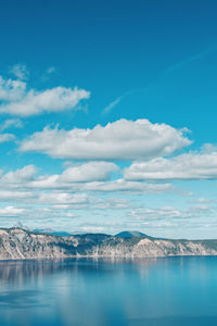 Scenic view of sea by mountain against sky