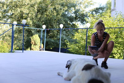 Full length of young woman photographing her dog