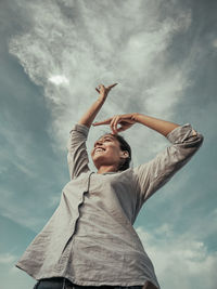 Low angle view of woman looking at camera against sky