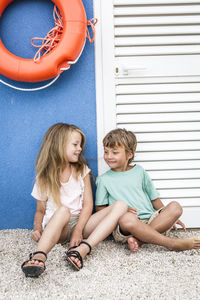 Siblings sitting outside closed door