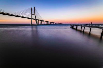 Bridge over sea against sky during sunset