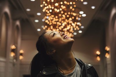 Woman looking up at illuminated decoration in home