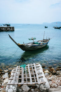 Fishing boats moored on sea against sky