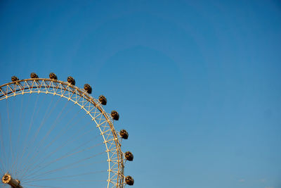 Low angle view of ferris wheel against clear blue sky