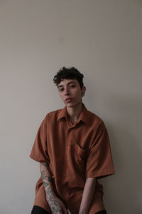 Portrait of young woman standing against wall