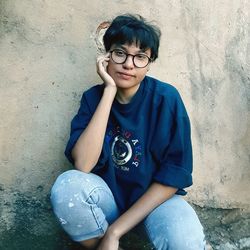 Portrait of woman sitting against wall