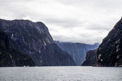 Scenic view of sea and mountains against cloudy sky