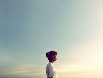 Low angle view of woman standing against sky during sunset