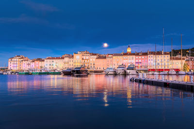 Buildings by river against sky