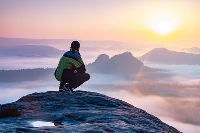 Rear view of man on mountain against sky during sunset