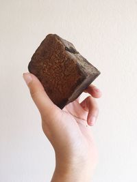 Close-up of hand holding bread against white background