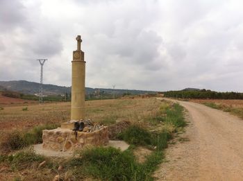 View of field against cloudy sky