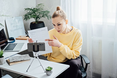 Passive income, side hustle ideas to earn at home. young woman speaking in front of camera for vlog