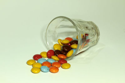 Close-up of multi colored candies in jar against white background