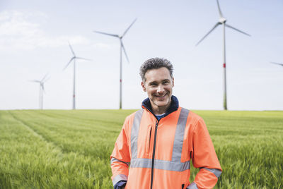 Smiling engineer in reflective clothing standing on field